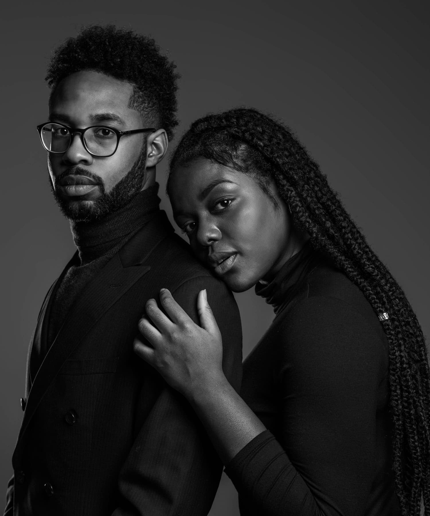 A couple posing together in a dark studio, shot in black and white