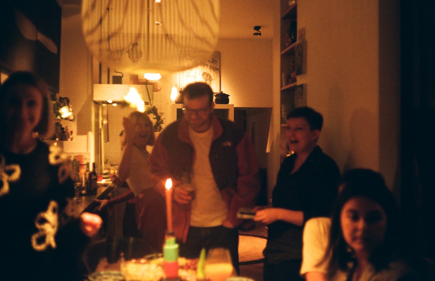 Friends gathered around a table in a warm, candlelit room