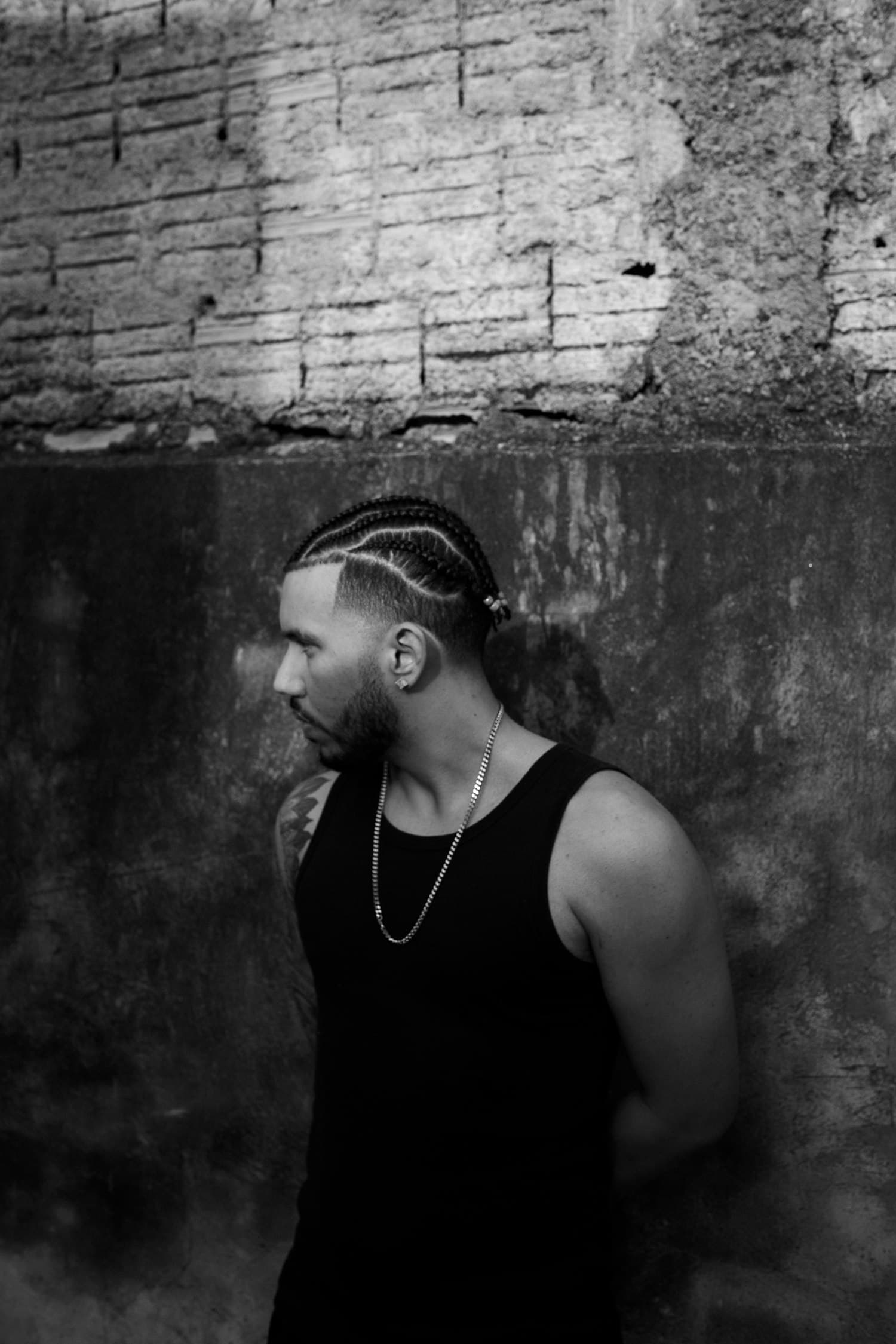 Profile portrait of a man against a concrete wall, in black and white