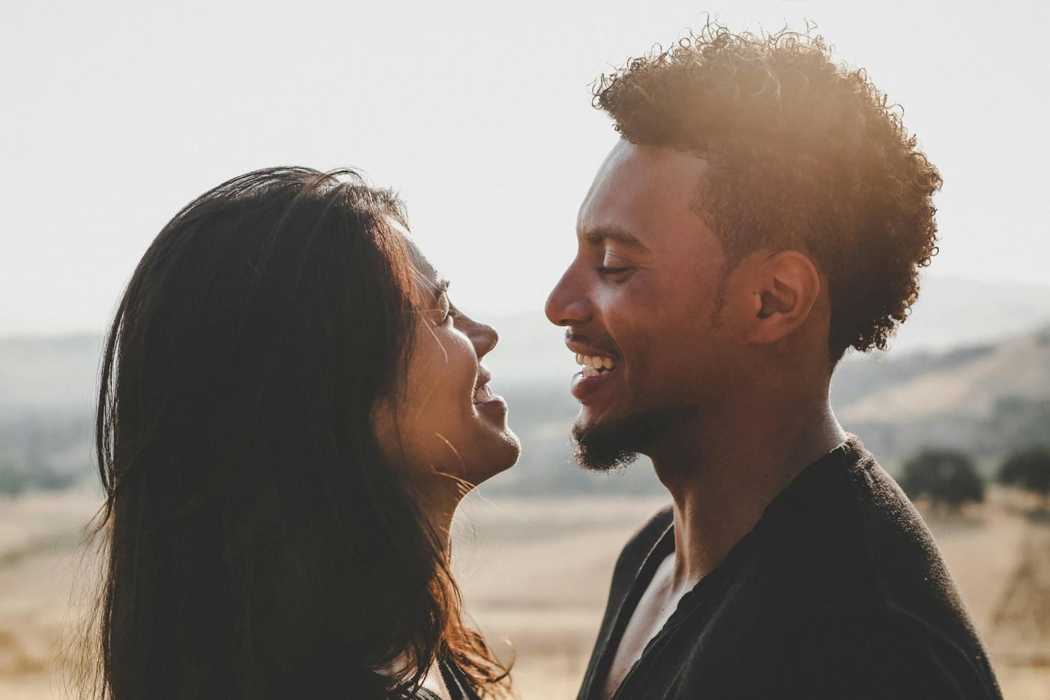 Priya and Marcus facing each other, laughing, backlit